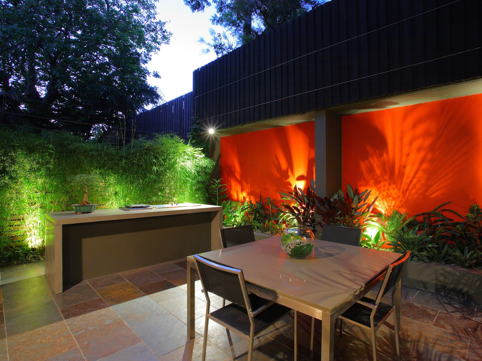 Large format Lichen split stone slate tiles used in small courtyard with BBQ area and red feature wall