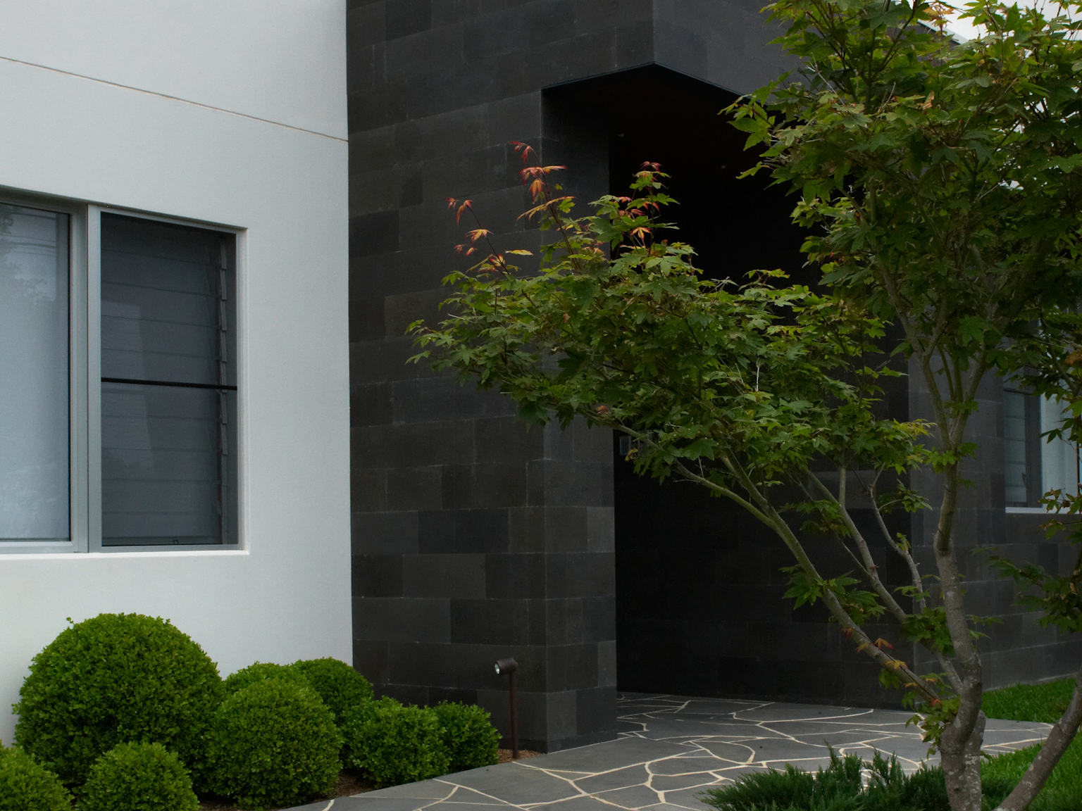 Residential facade clad with Honed bluestone traditional format walling and bluestone crazy paving pathway