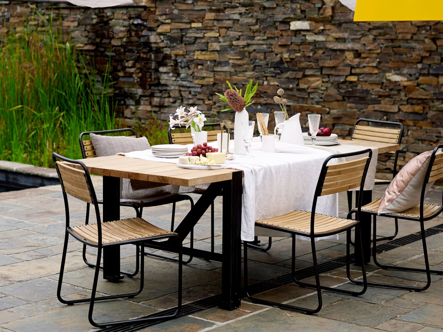 Turon dining chairs with Colo dining table in outdoor dining area with Badger dry stone walling 