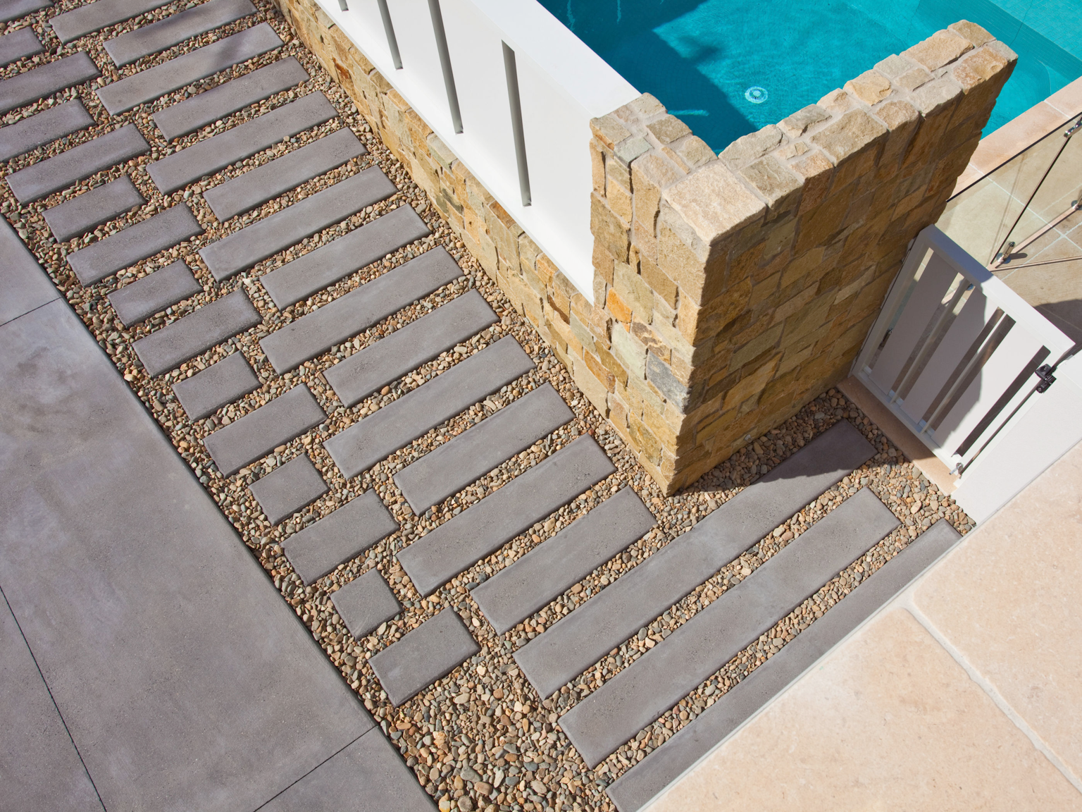 Basalt concrete pavers and stepping stones of driveway with Clancy random ashlar walling on pool fence. La Roche limestone around the pool.