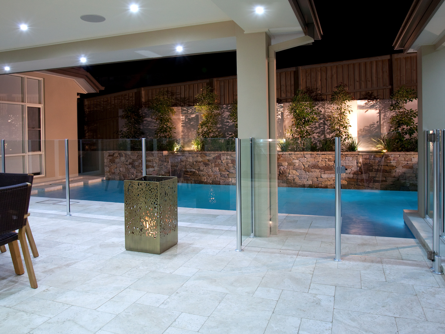 Ravello travertine modular flooring in outdoor dining area with Alpine dry stone walling in pool area