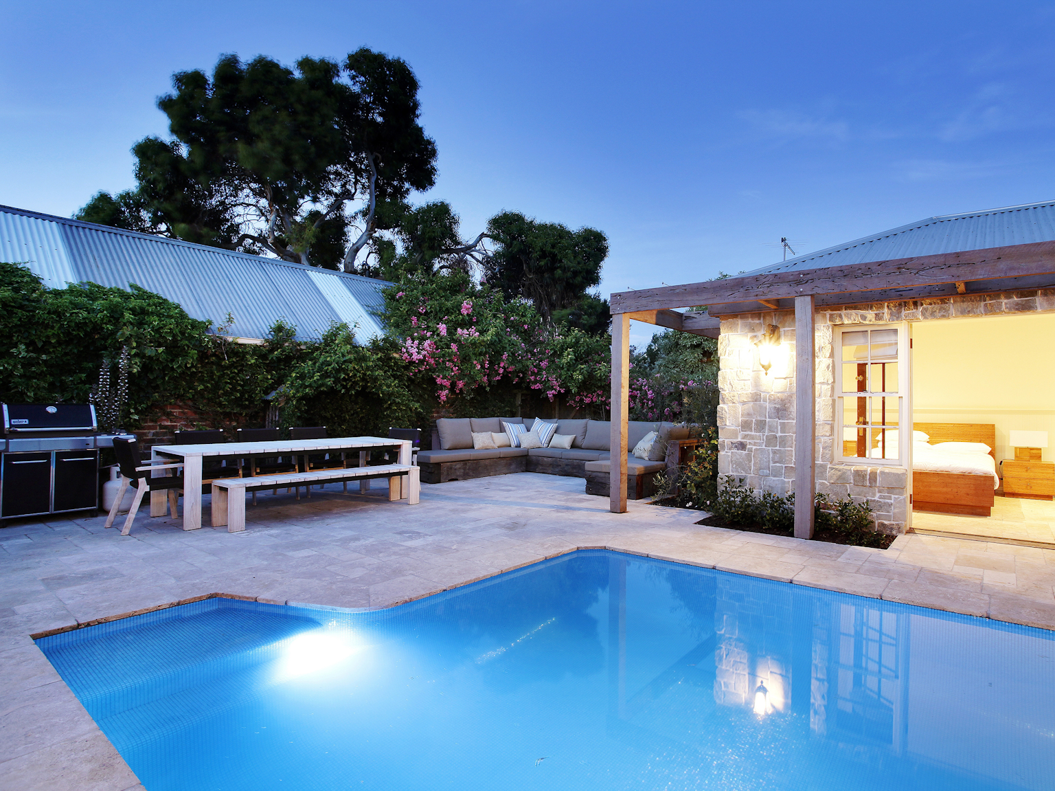 Capri travertine modular paving used as pool surround with Clancy sandstone random ashlar cladding on exterior of pool house 