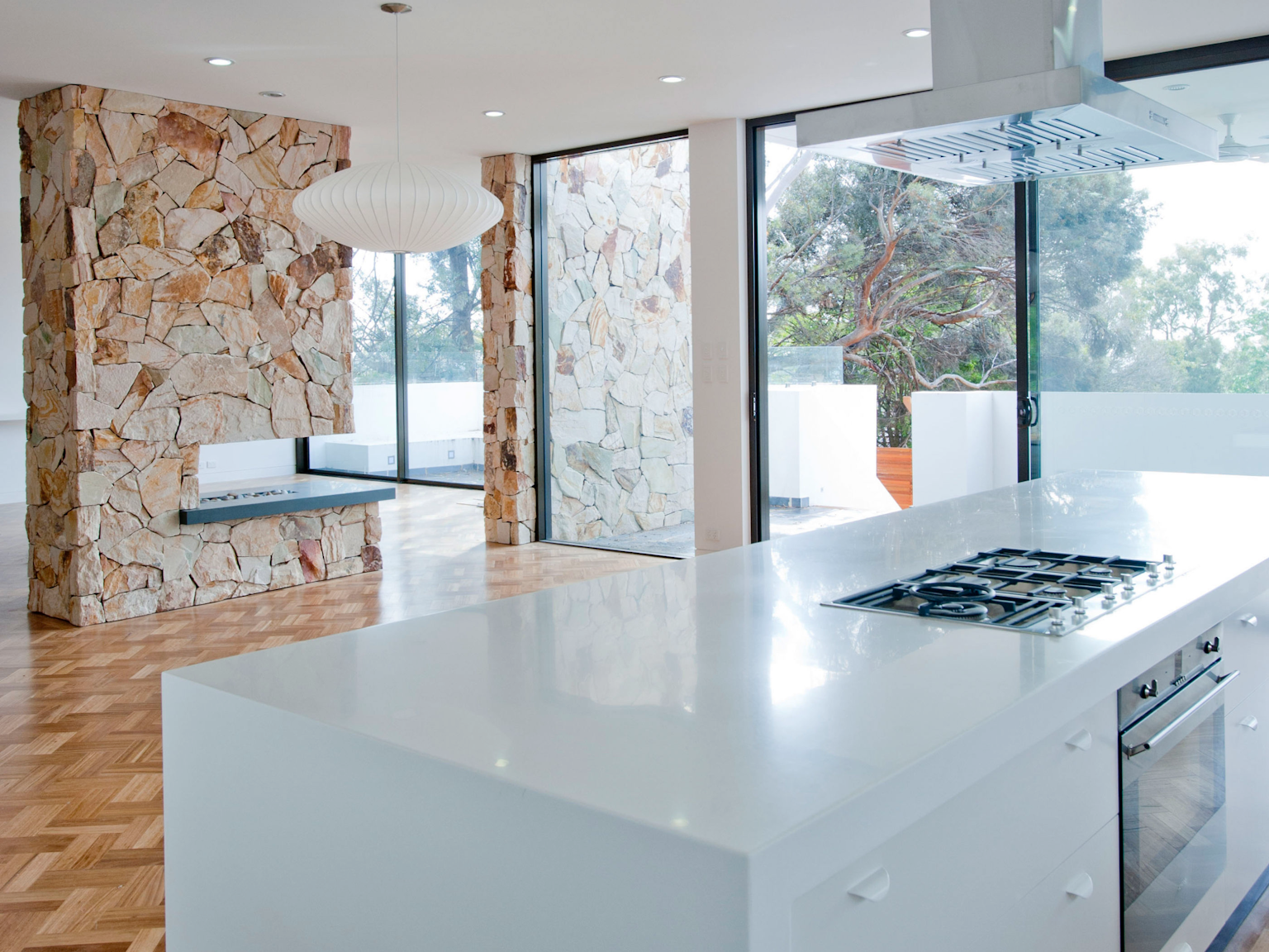 Kitchen and living space with internal fireplace and blade wall in Crackenback sandstone free form cladding