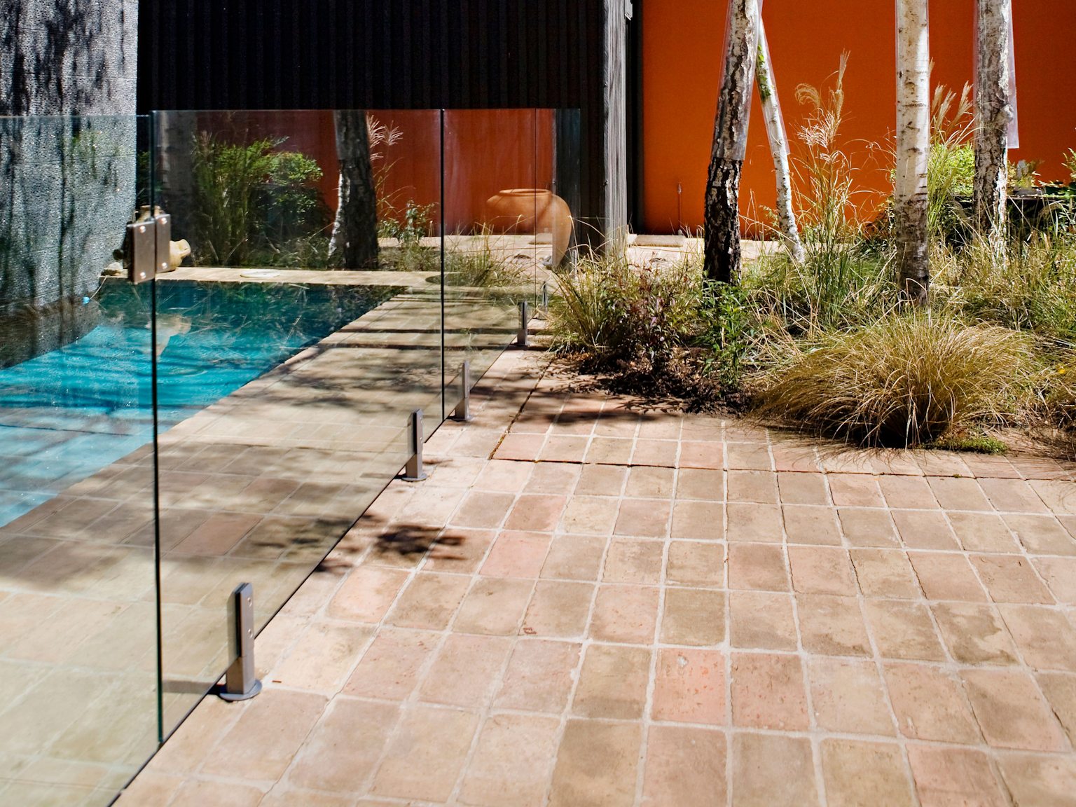 View  along pool fencing of Antico Luce terracotta pavers used in garden area