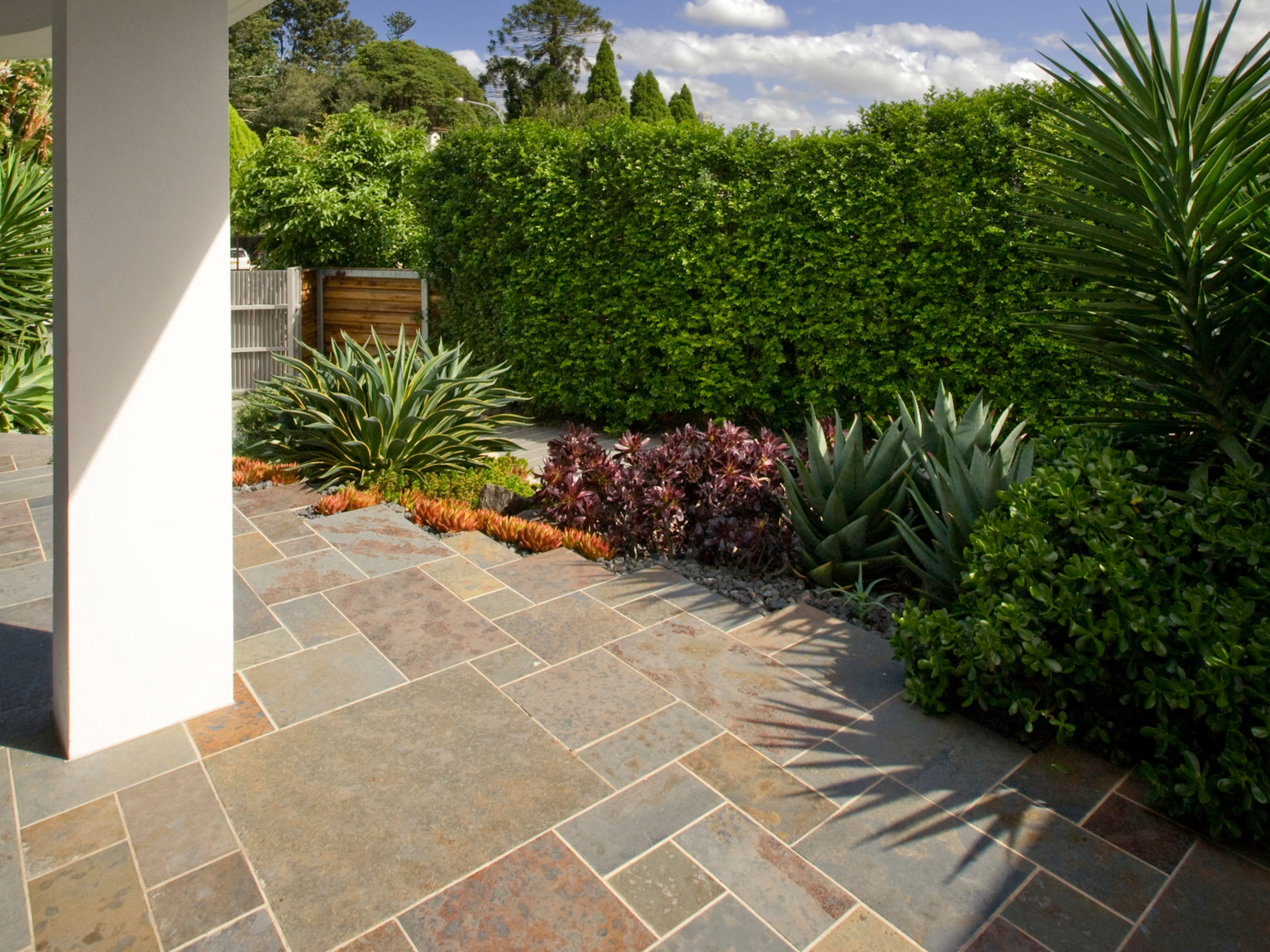 Patio using Lichen split stone slate modular paving flowing into garden bed