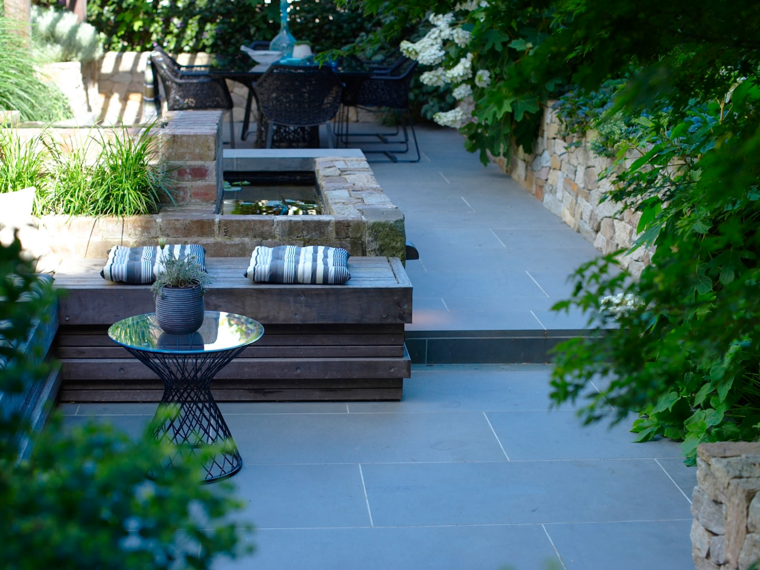 Courtyard garden with large format bluestone pavers and Alpine dry stone retaining walls with water feature