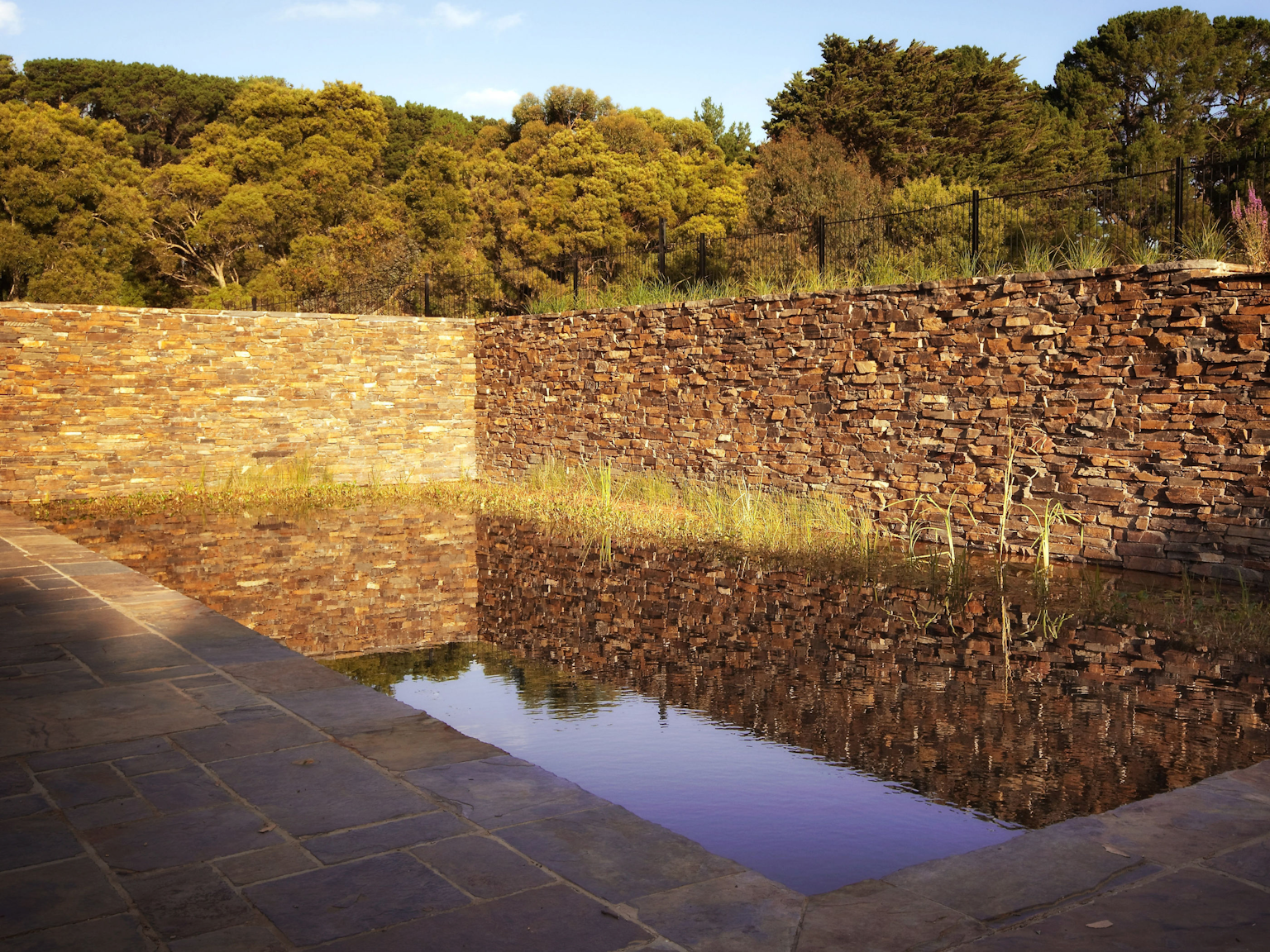 Myrtle split stone paving used around natural billabong pool with Badger dry stone retaining walls