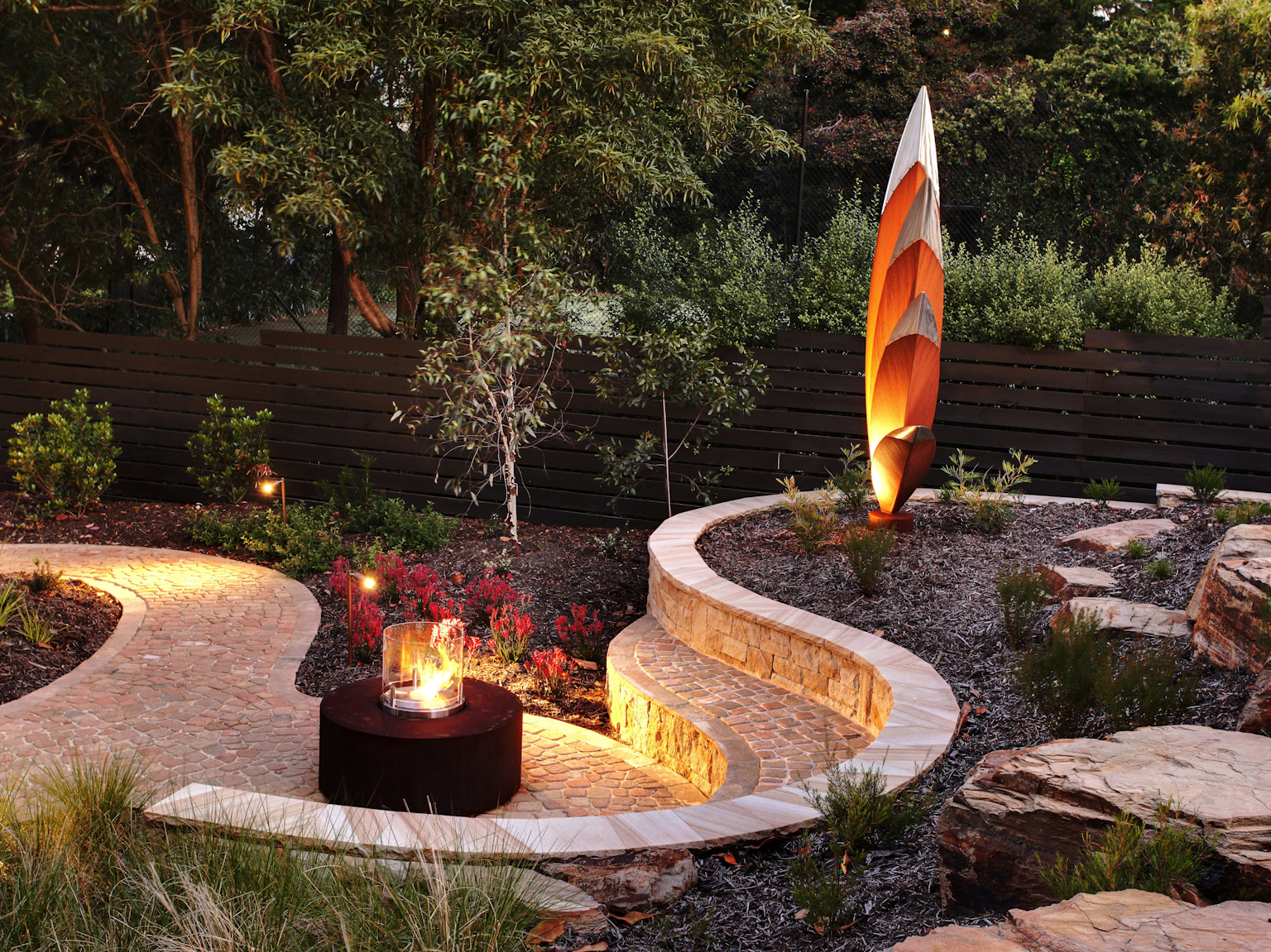 Fire pit with stone bench seat in Antico luce terracotta pebbles and retaining wall in Killcare random ashlar sandstone 