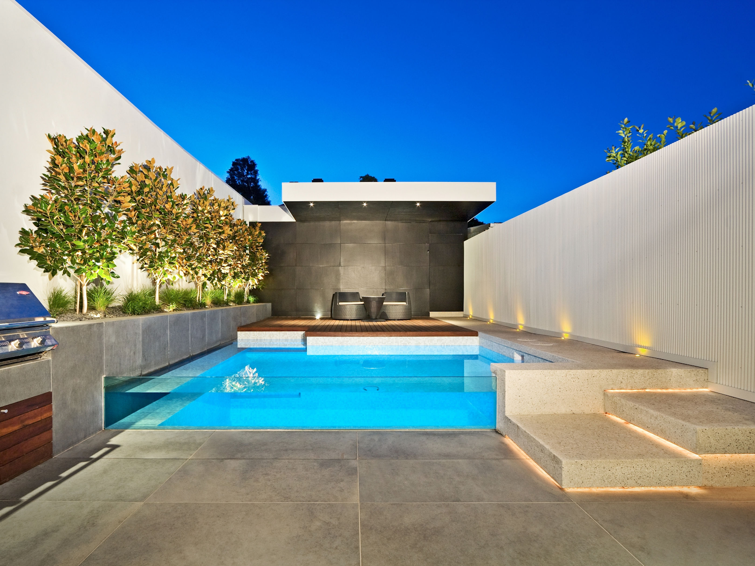 Contemporary pool with large format bluestone pavers used as flooring and walling in pool area 