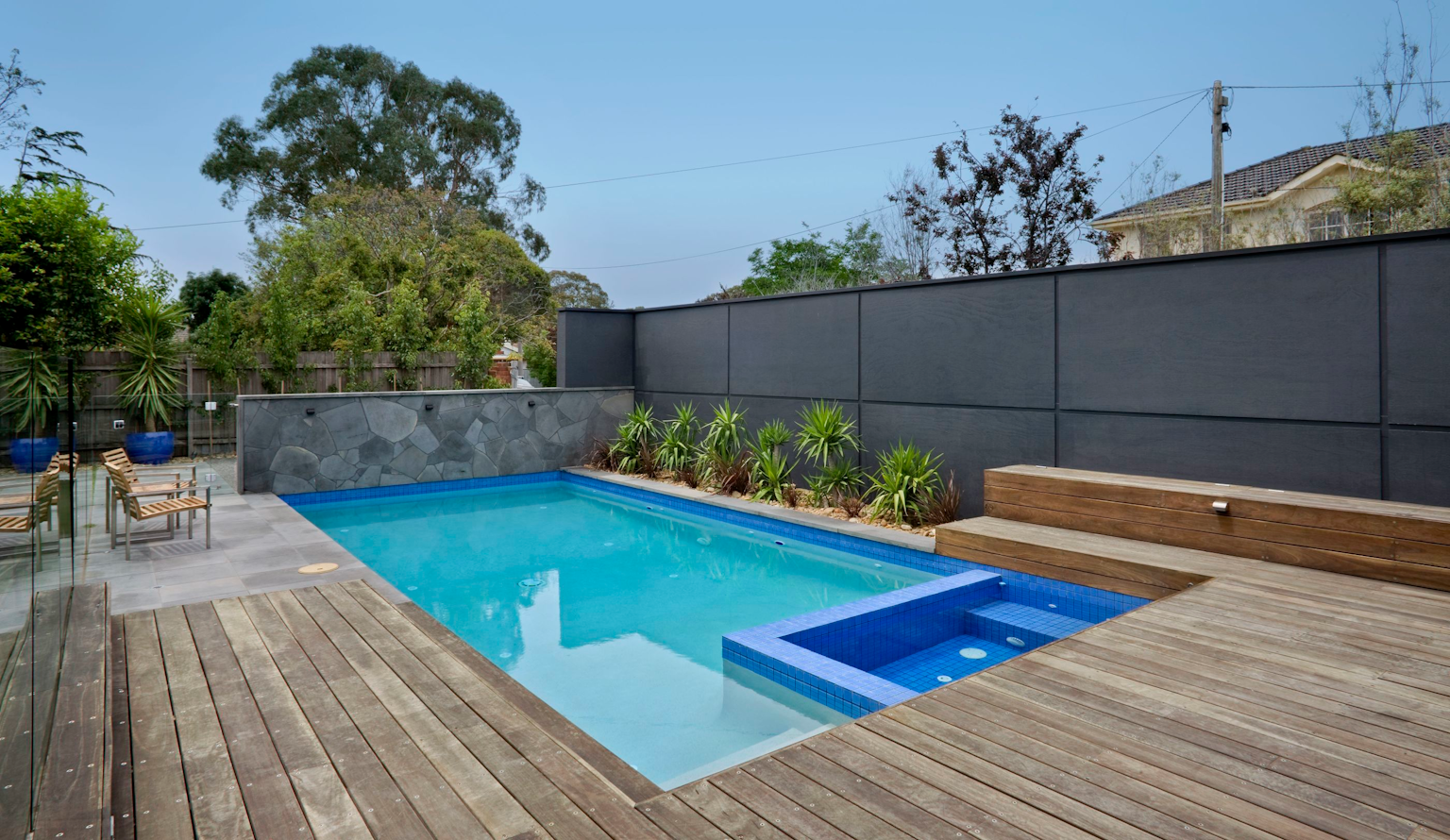 Modern pool with bluestone paving & feature wall